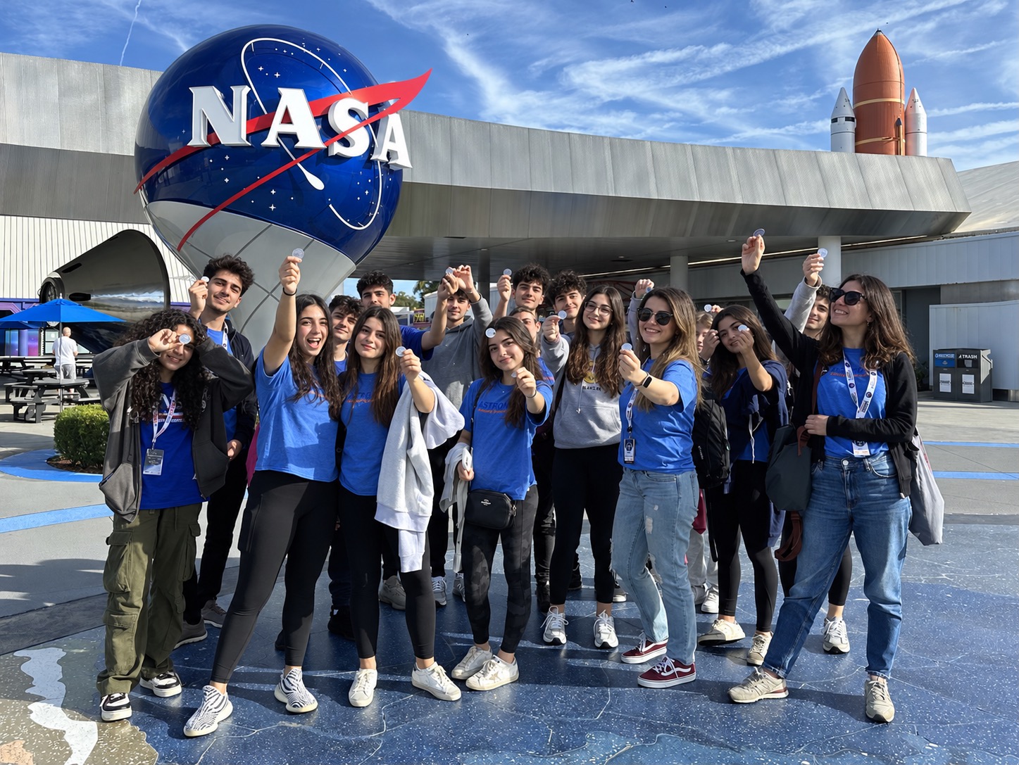 nasa-arsiv-son NASA logosu önünde eğitim gezisi grubu; yüzleri ve logo boyutu düzenlenmiş fotoğraf
